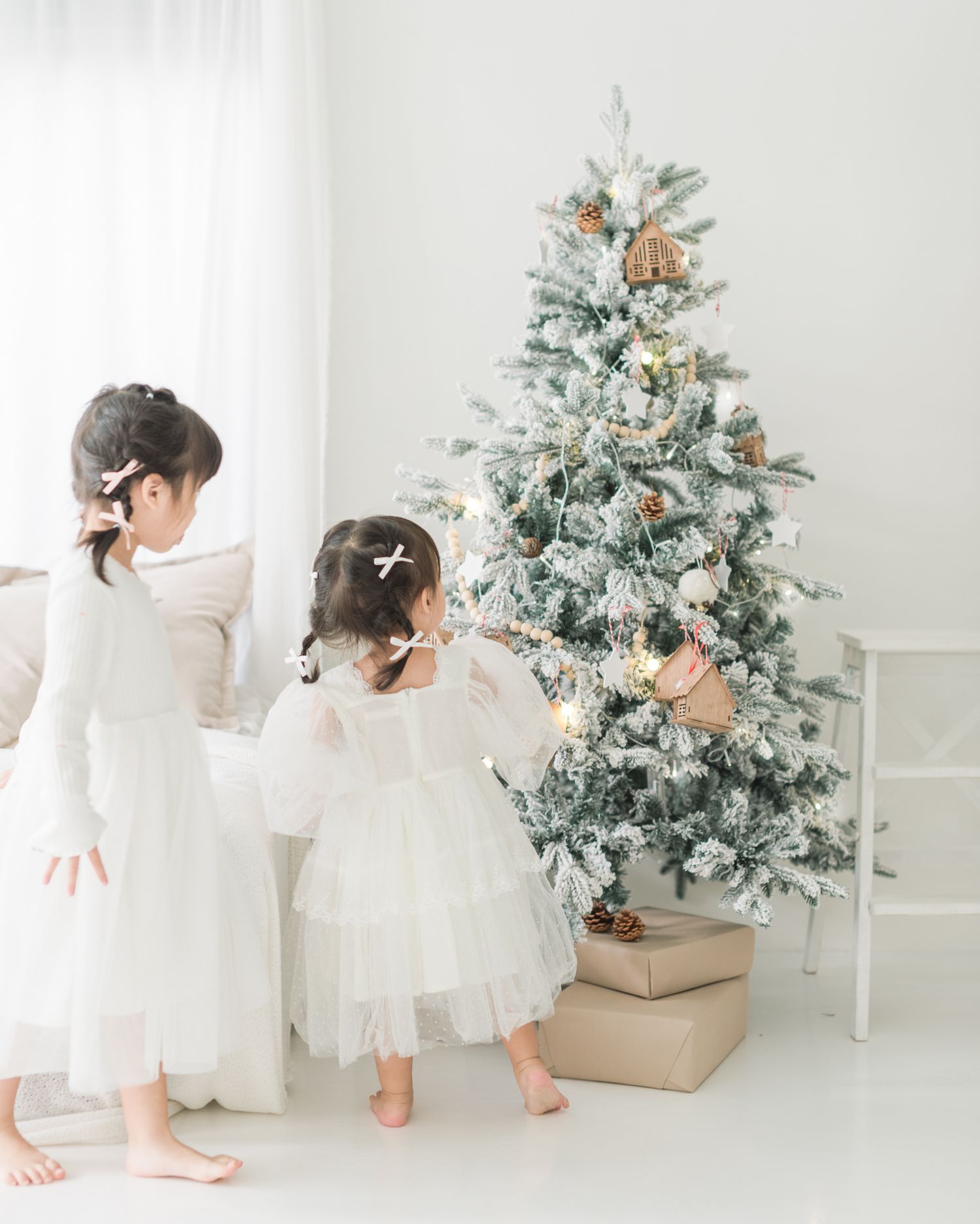 White Christmas photo session setup with flocked tree and wrapped presents in a bright studio setting.