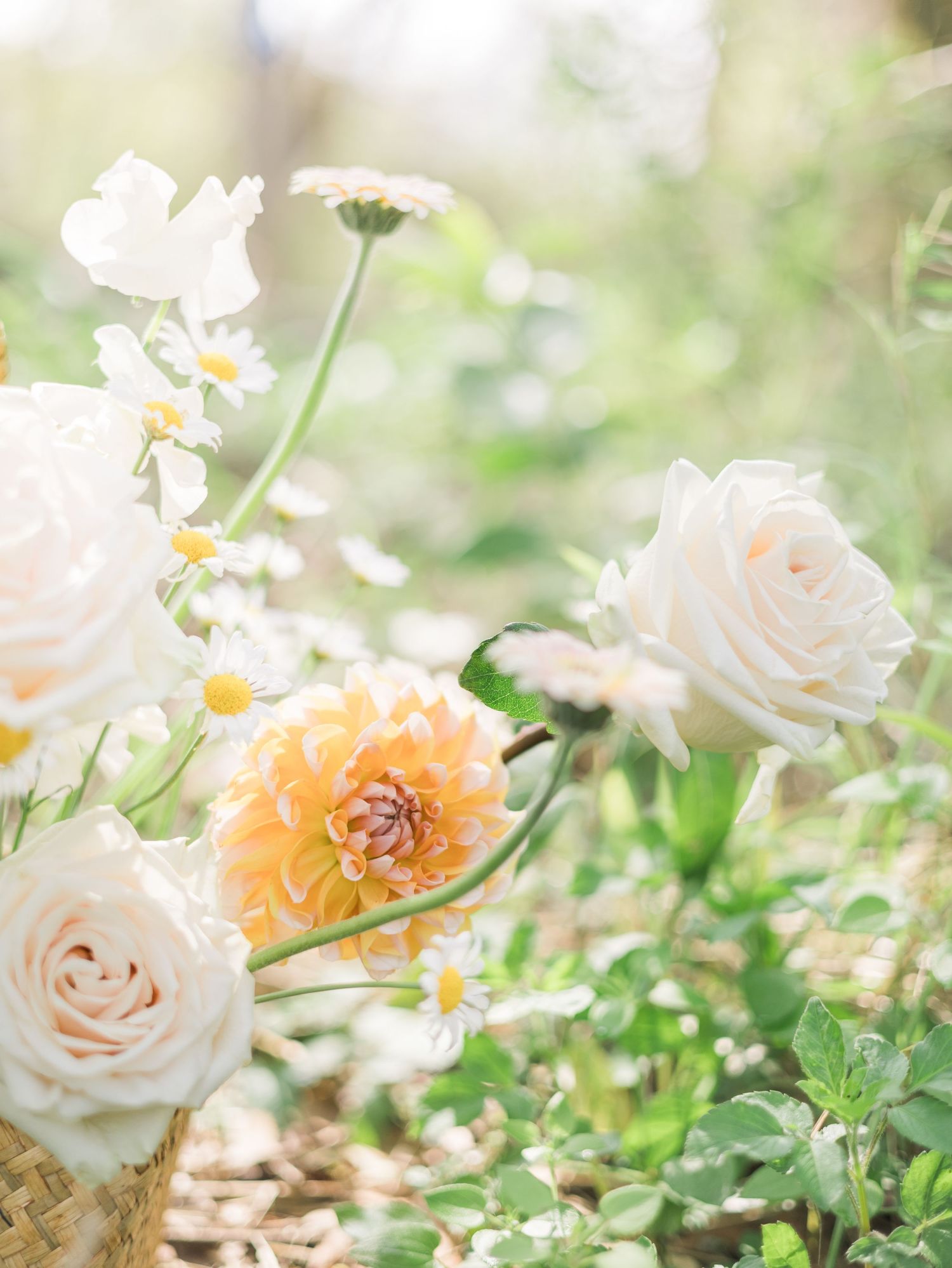 Delicate arrangement of white roses and peachy dahlias with daisies in soft natural light.