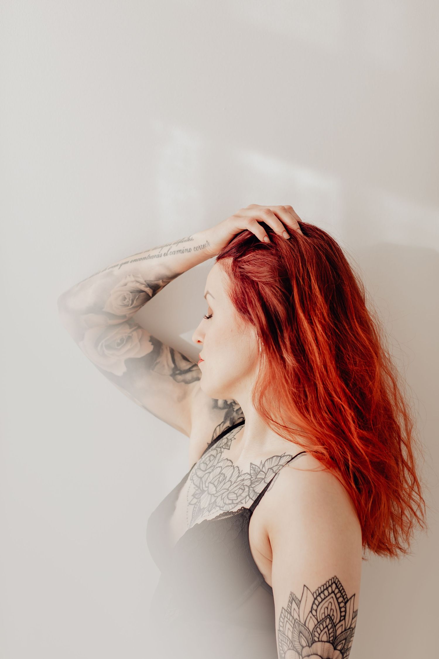 Tatuoitu nainen nautiskelee olostaan boudoir-kuvauksessa.
