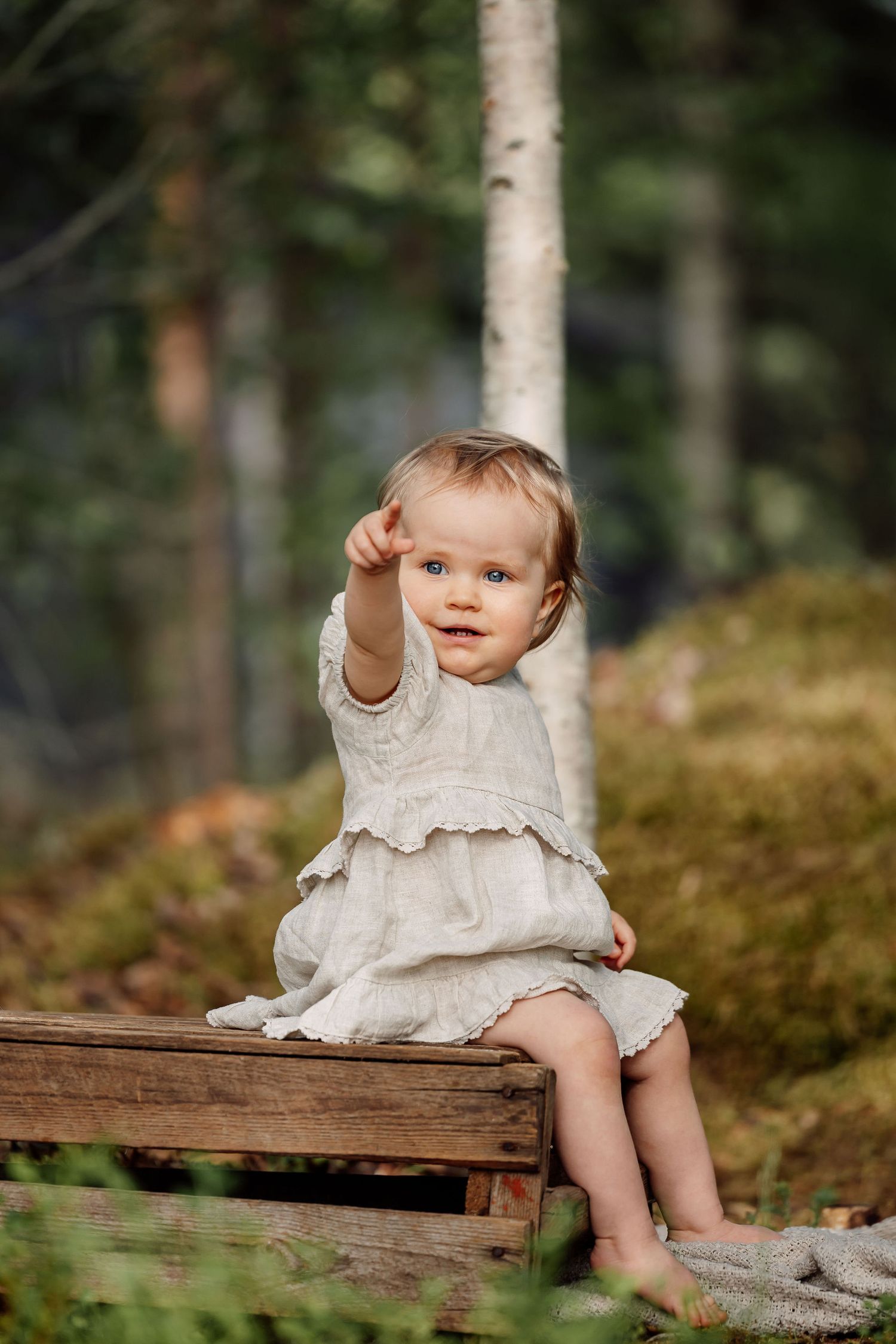 Yksivuotias istuu puulaatikon päällä ulkona