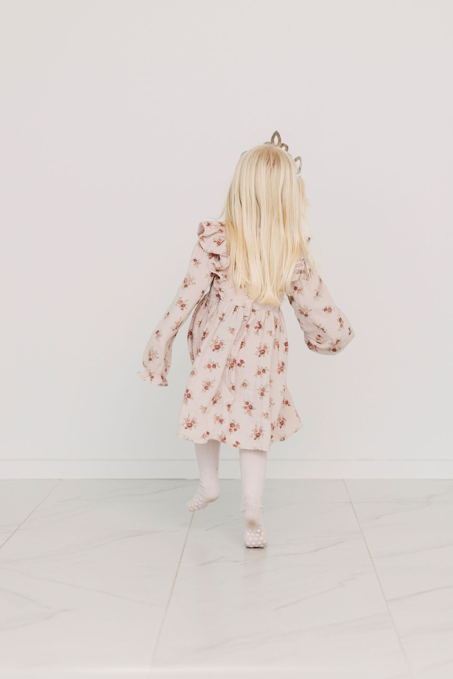Lapsi hyppelee iloisesti prinsessakruunu päässään.