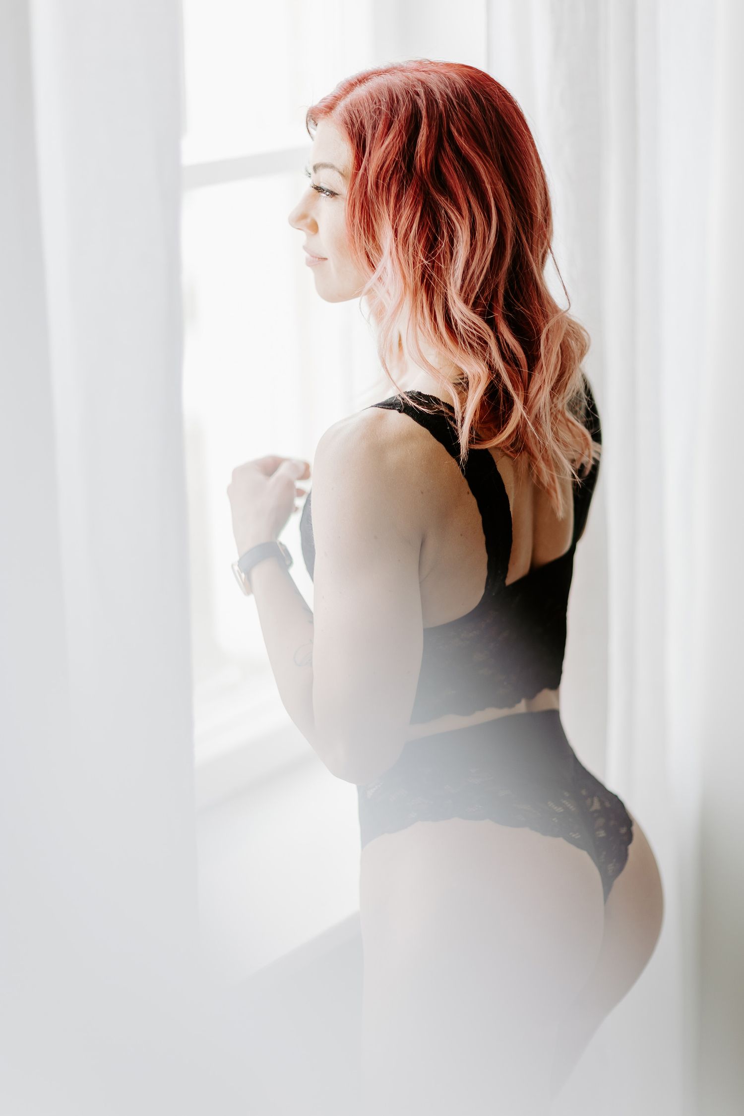 Nainen katselee ikkunasta boudoir-kuvauksessa.