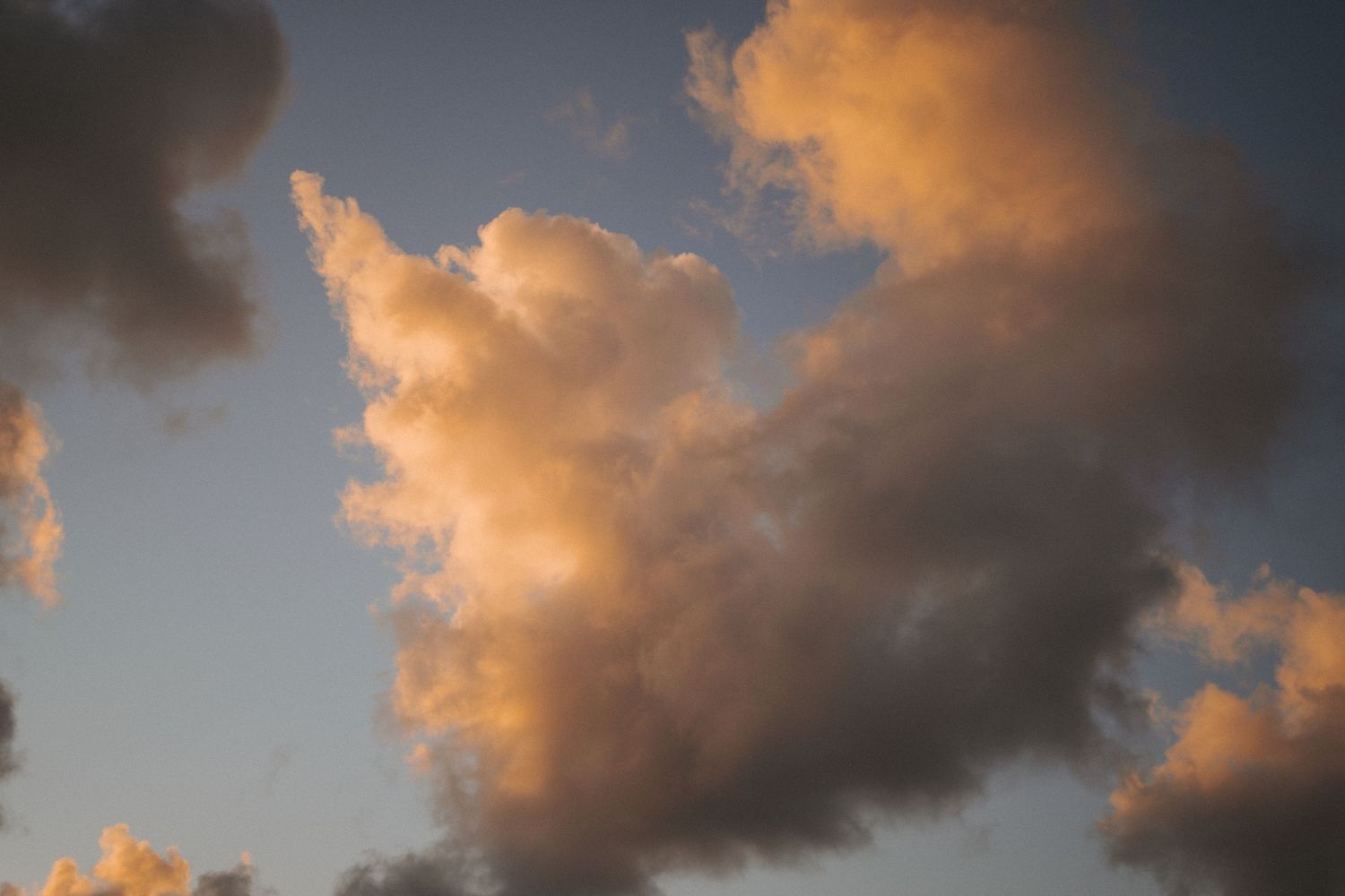 Dramatic golden sunset clouds illuminated in warm orange and pink tones against a blue sky.