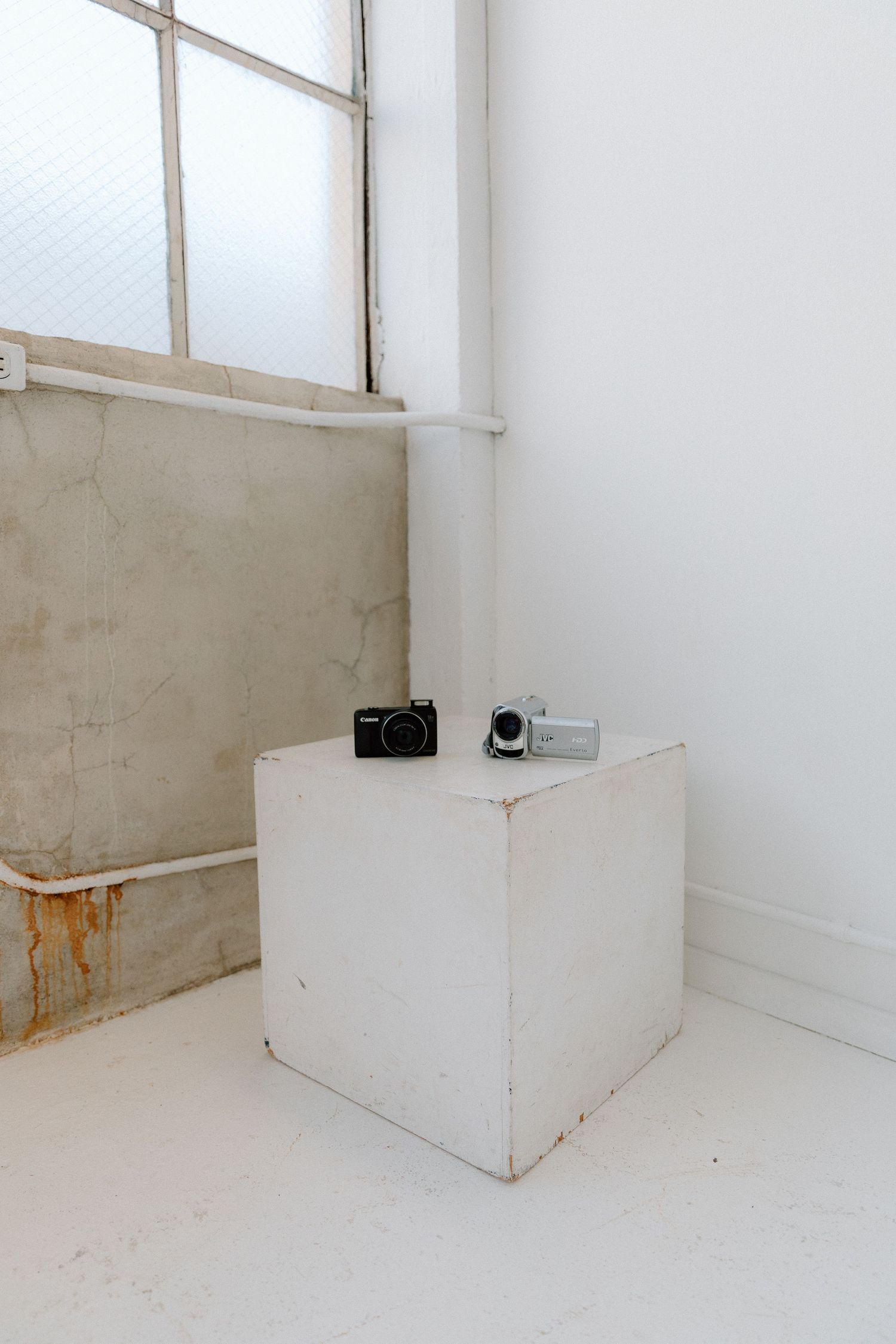 Photo of a digital camera and 90's camcorder showcased within a studio