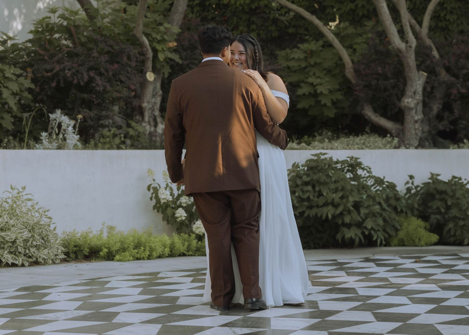 Bride beaming at groom during first dance at travel wedding in Geyserville, California at Catelli's Restaurant for the reception.