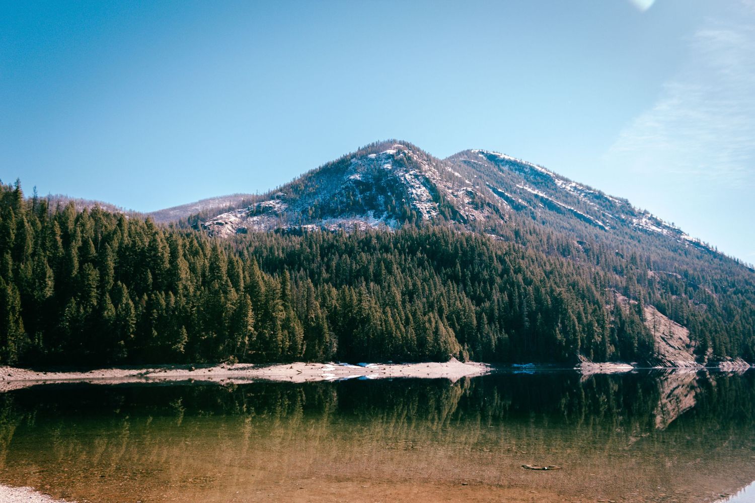 Snowy mountains beyond forested hills Lake Sullivan Northern WA.