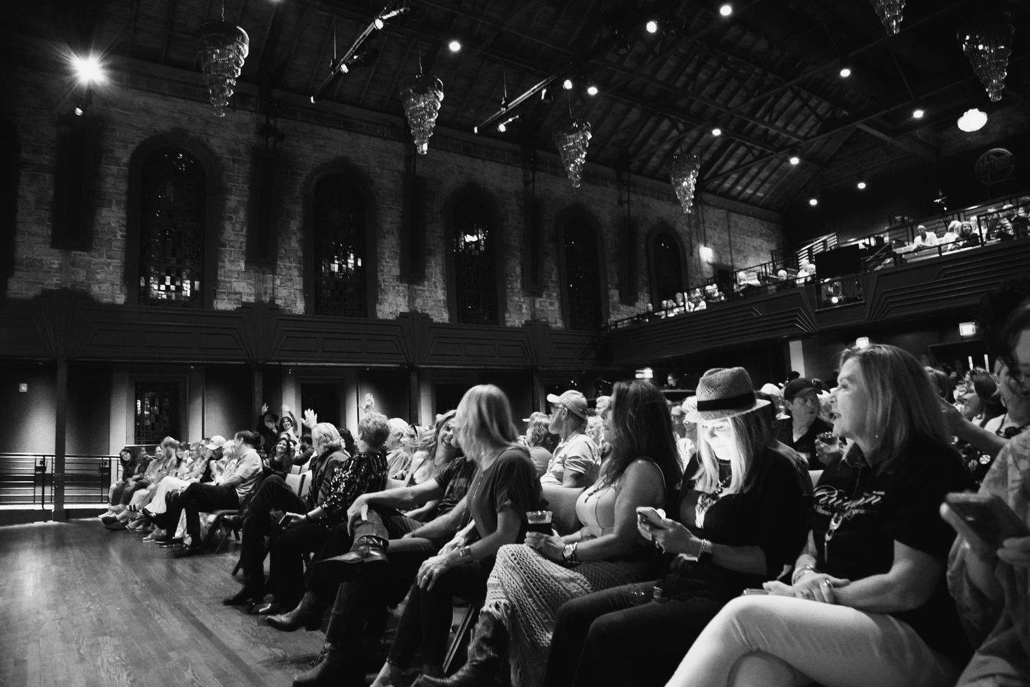 Black and white photo of an elegant theater audience seated in ornate venue during a live performance event.