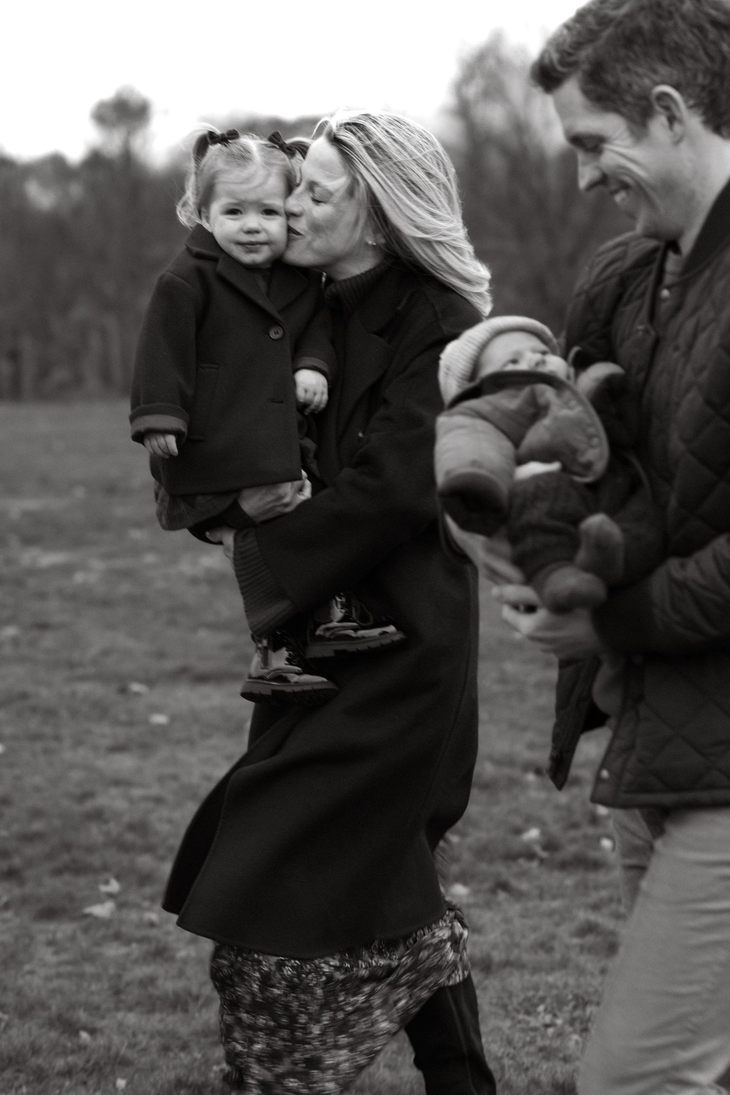 A candid black and white family moment outdoors showing affection and togetherness on a winter day.