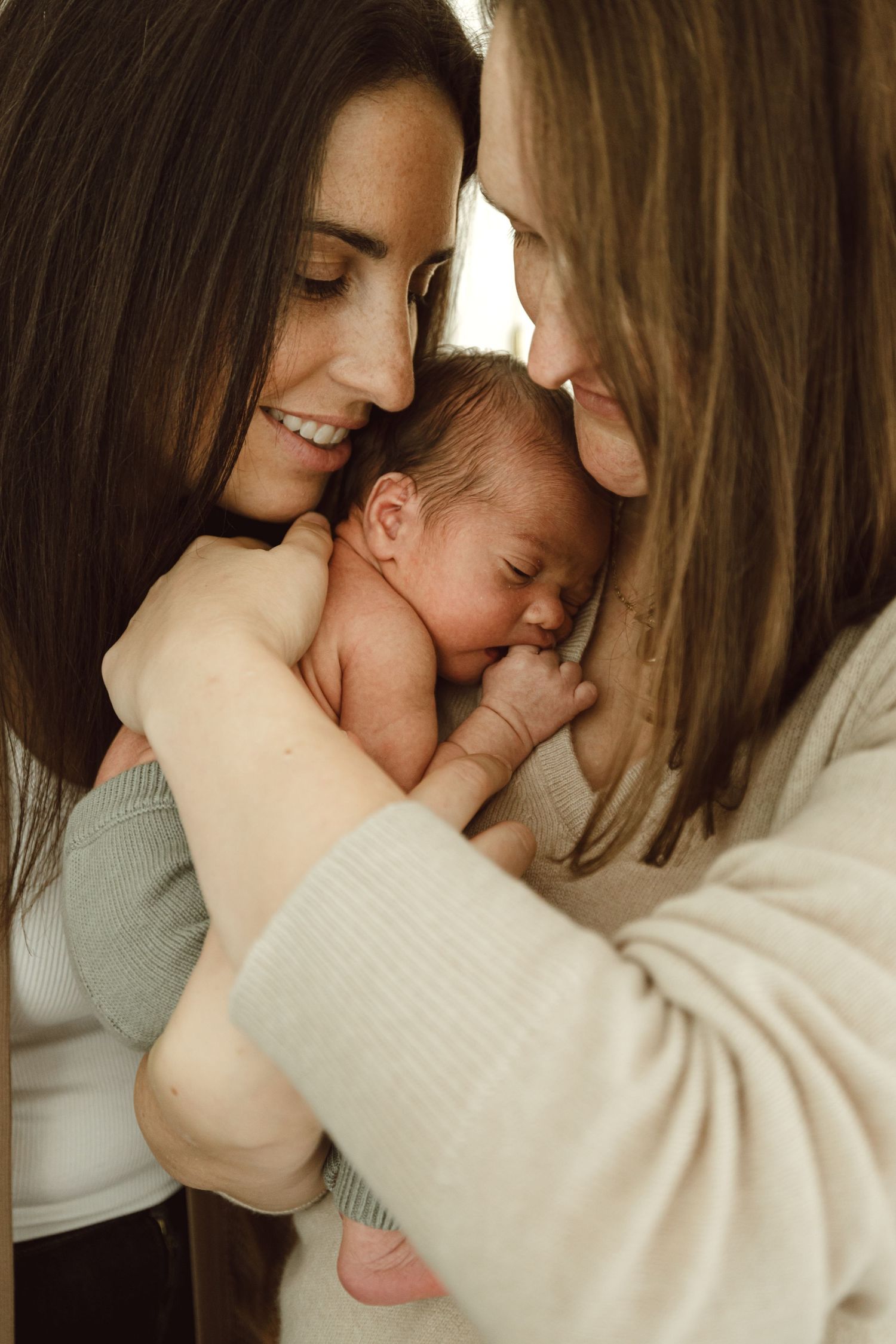 Lesbian Mothers hold their newborn baby boy lovingly during a Connecticut newborn photoshoot.