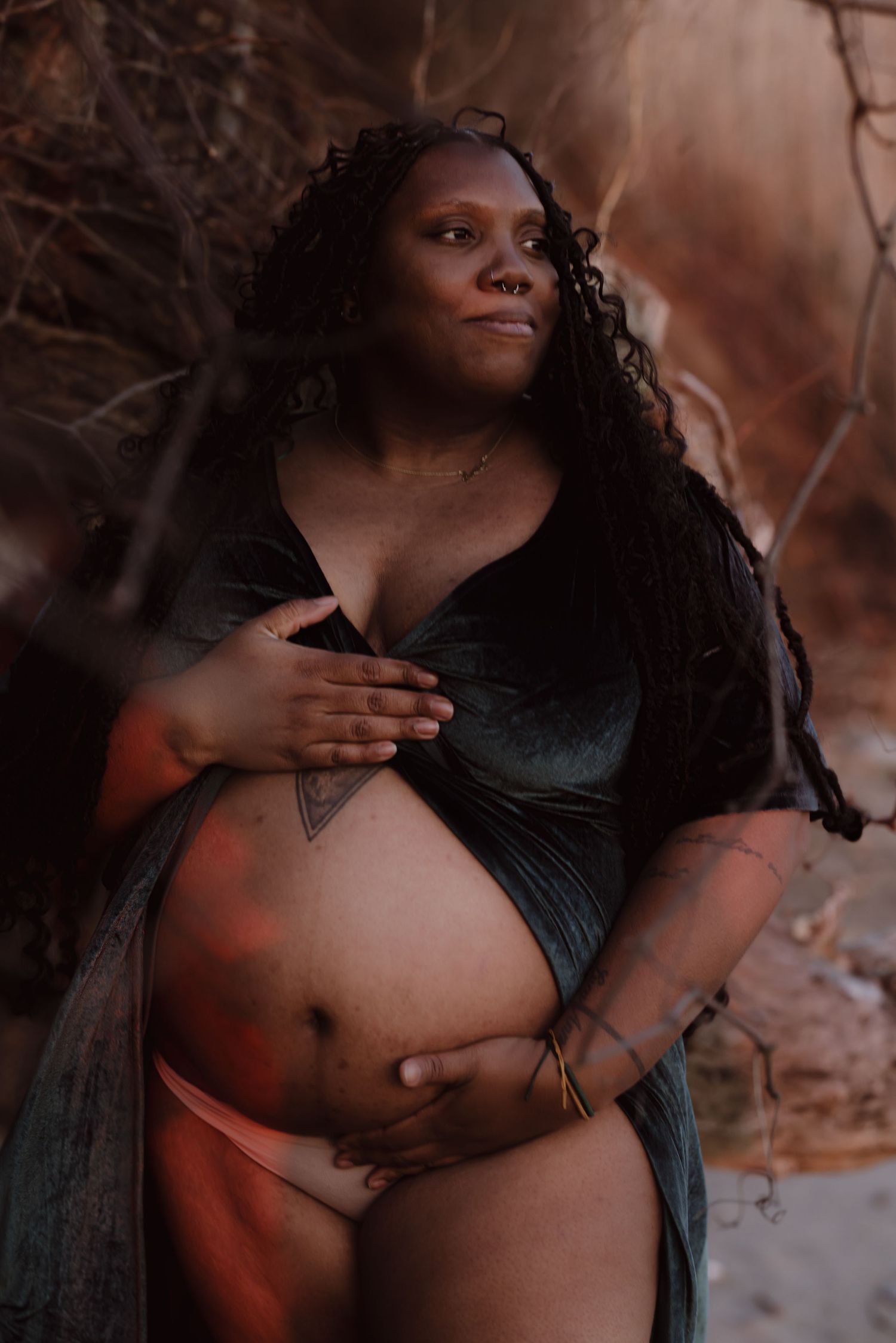 Artistic maternity photoshoot featuring dramatic shadows and intimate poses against a textured stone background.