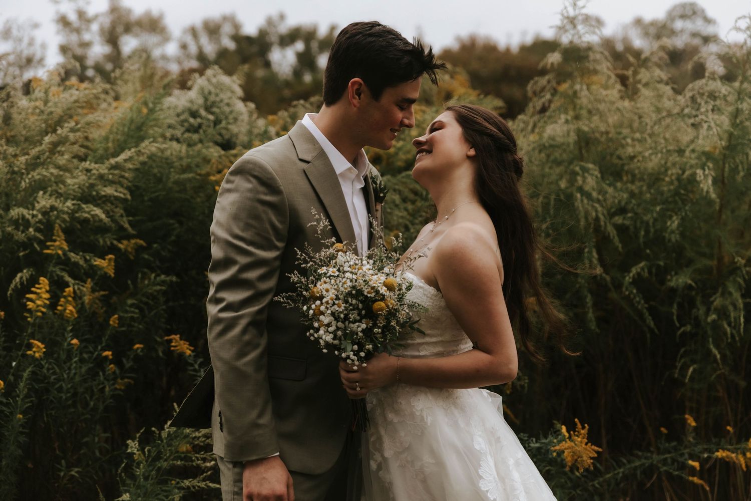 Romantic wedding couple poses in a field of wildflowers during golden hour.