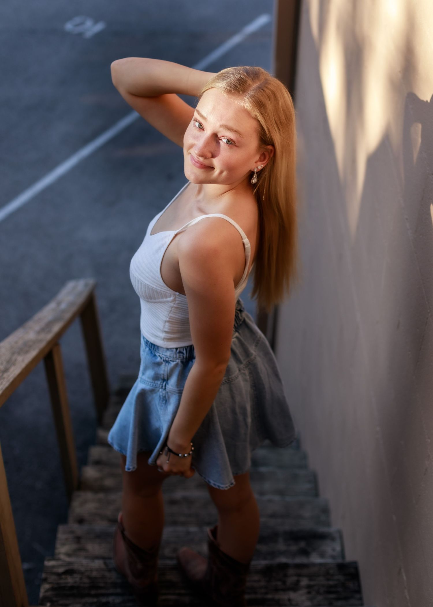 A woman in a gray tank top and jeans poses dramatically against a wall in a series of connected photos.