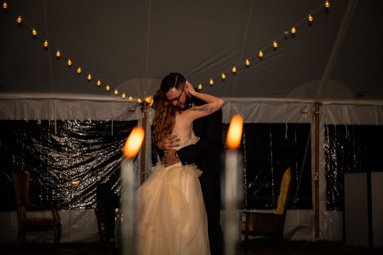 String lights illuminate an outdoor wedding reception tent creating a romantic evening ambiance.