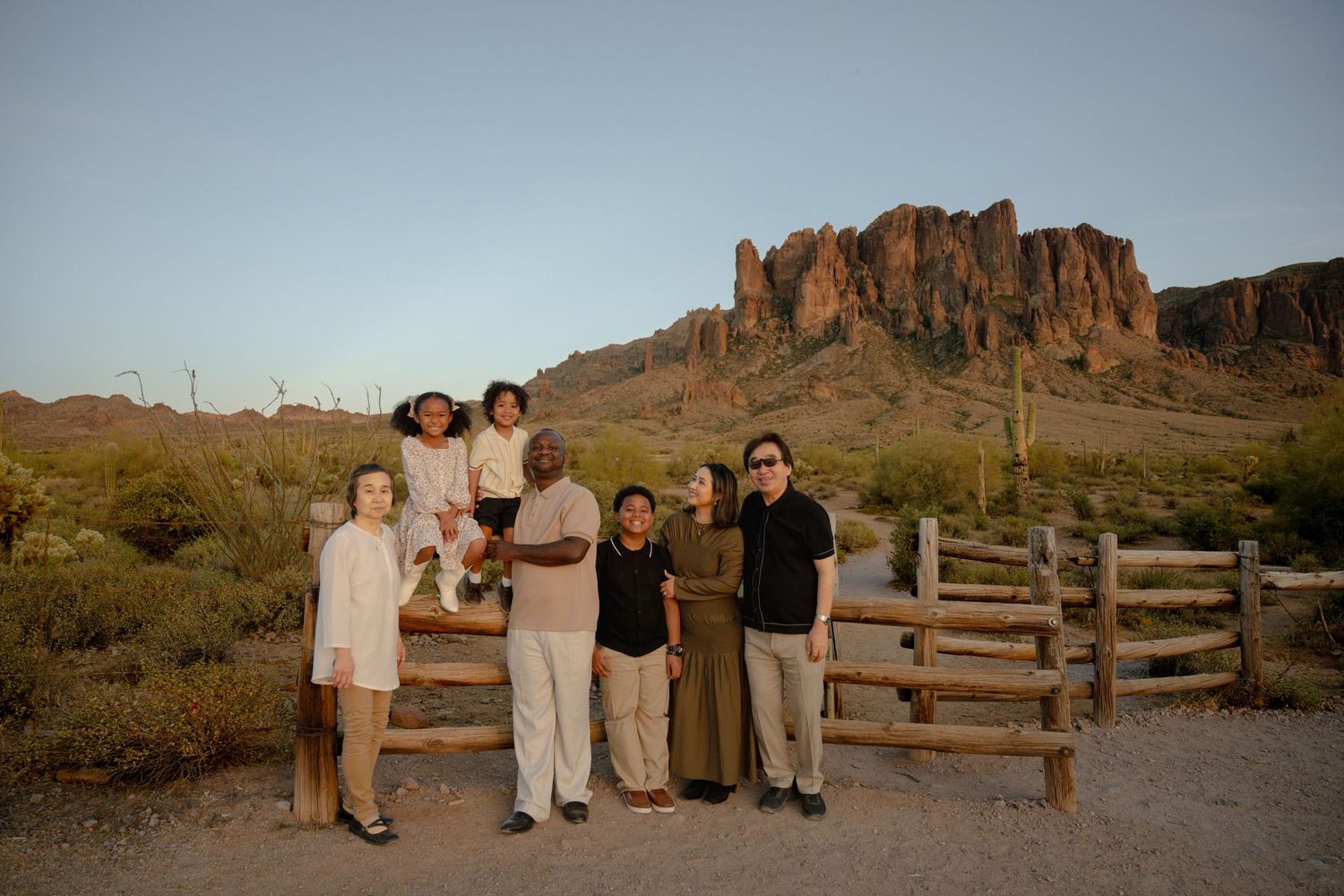 Multi-generational family smiles together at dusk with iconic Arizona Superstition Mountains backdrop.