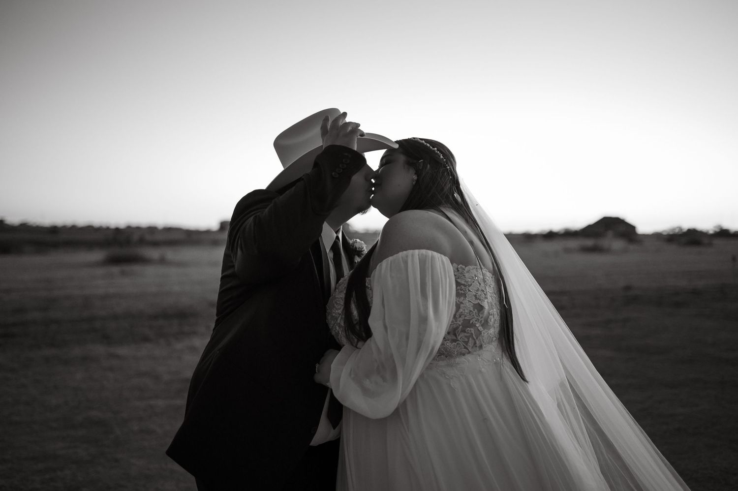 Black and white romantic wedding portrait in an open field at dusk.
