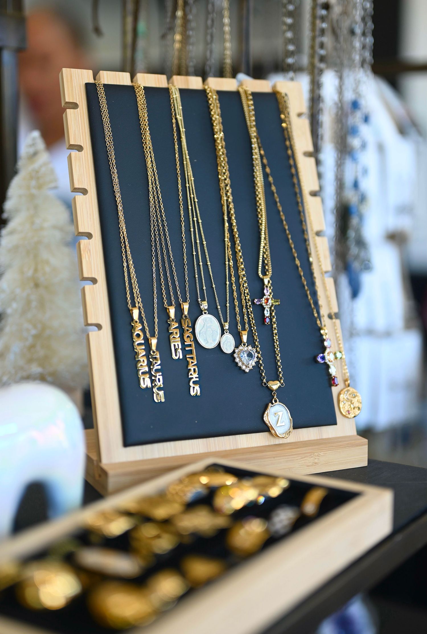 Collection of gold chain necklaces with zodiac pendants arranged on navy velvet display board.