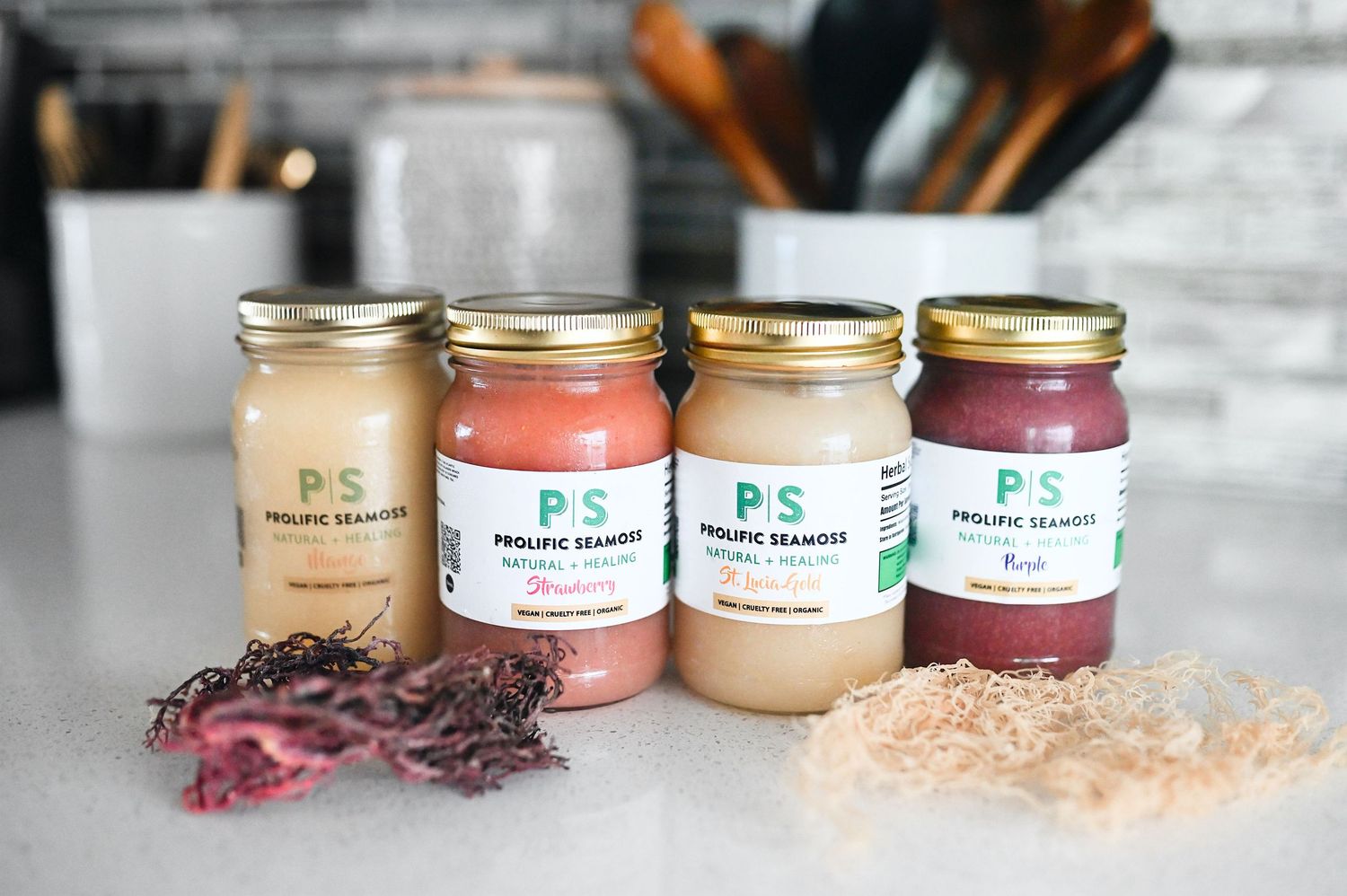 Four glass jars of Prolific Seamoss wellness products on kitchen counter.