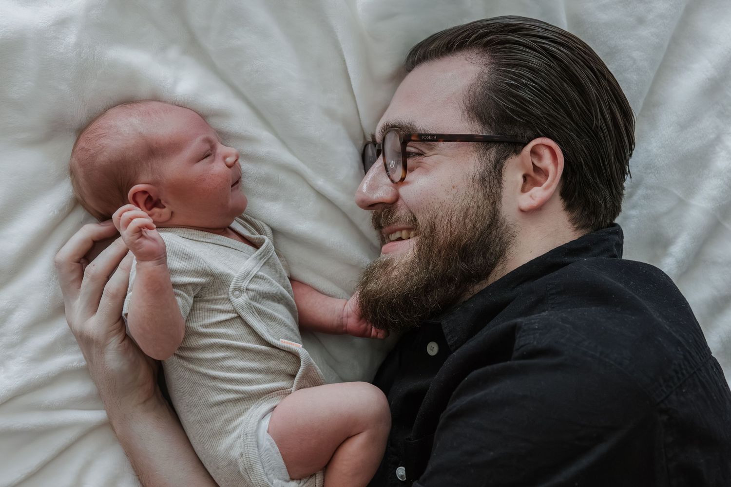 Pure newbornfoto van een pasgeboren baby in een warme, huiselijke omgeving.