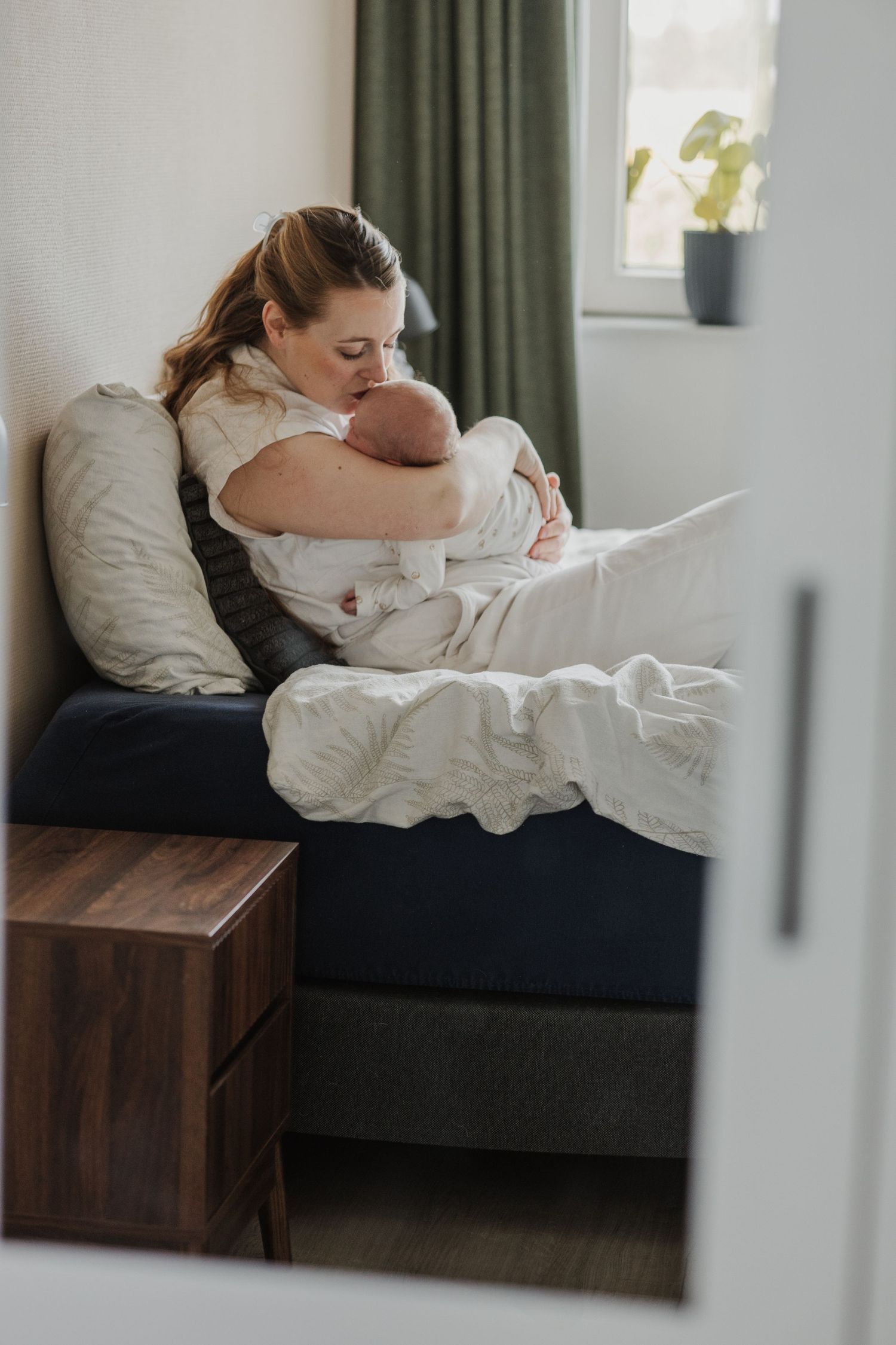 Pure newbornfoto van een pasgeboren baby in een warme, huiselijke omgeving.