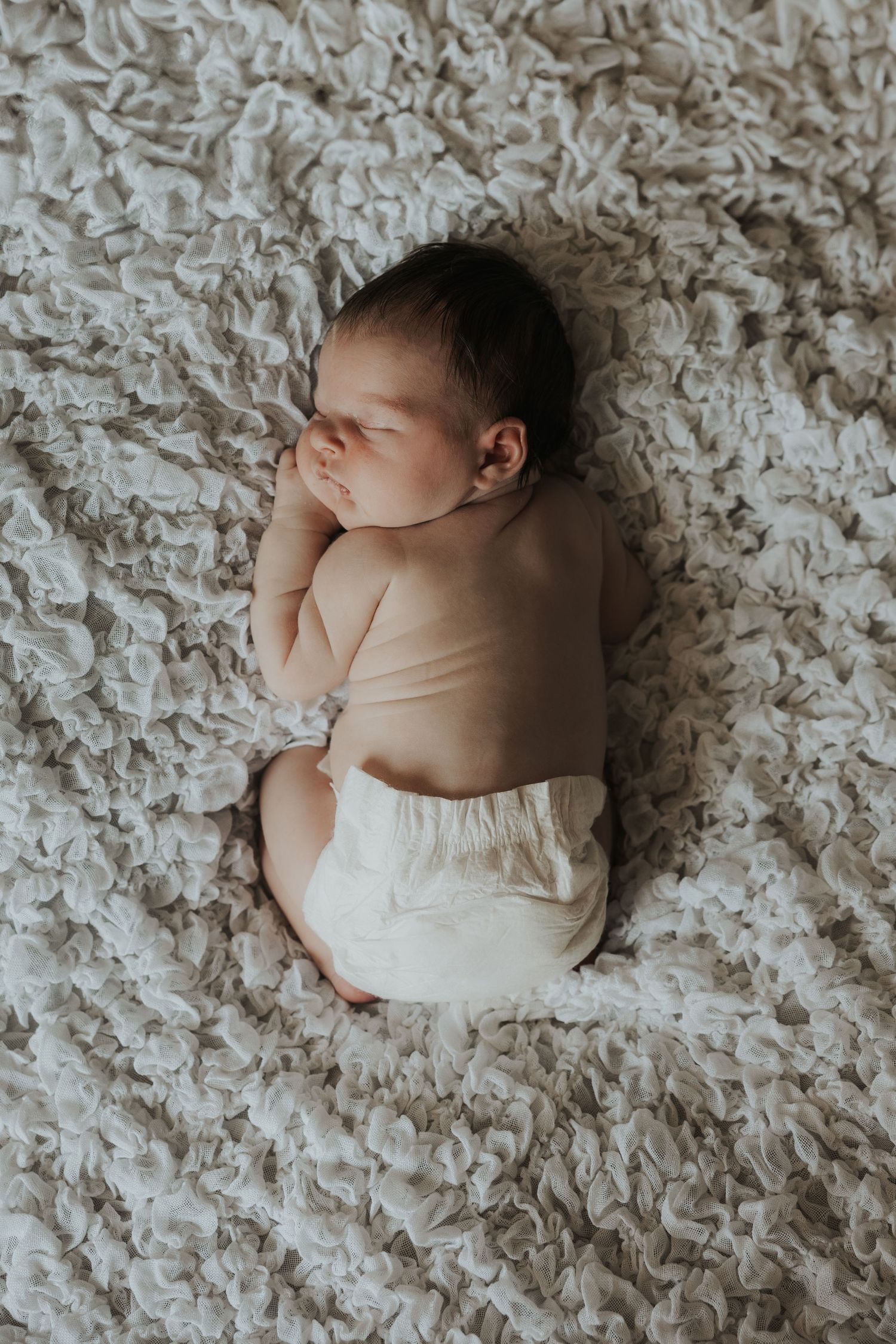 Pure newbornfoto van een pasgeboren baby in een warme, huiselijke omgeving.