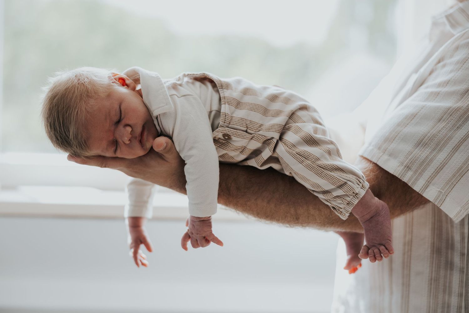 Pure newbornfoto van een pasgeboren baby in een warme, huiselijke omgeving.
