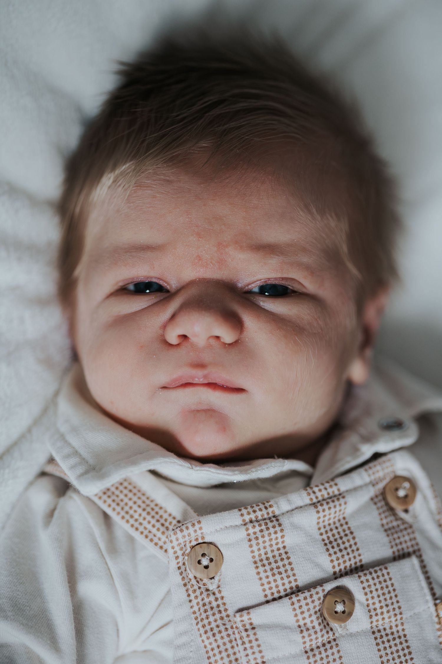 Pure newbornfoto van een pasgeboren baby in een warme, huiselijke omgeving.