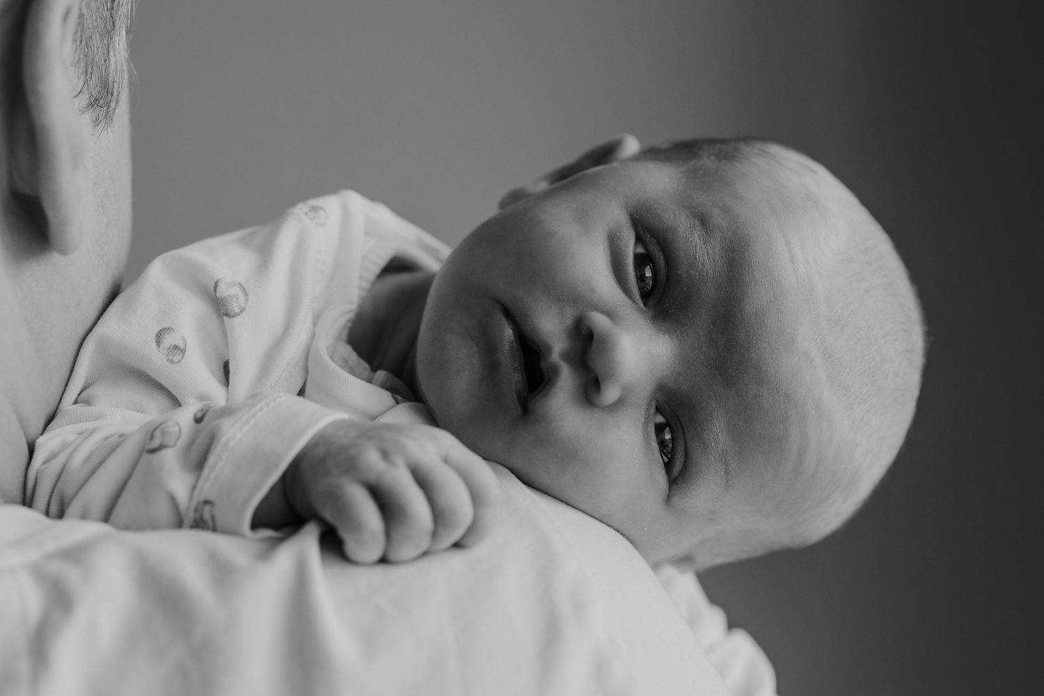 Pure newbornfoto van een pasgeboren baby in een warme, huiselijke omgeving.