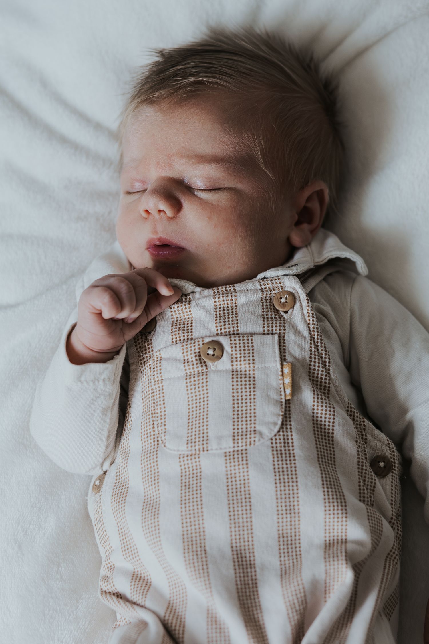 Pure newbornfoto van een pasgeboren baby in een warme, huiselijke omgeving.