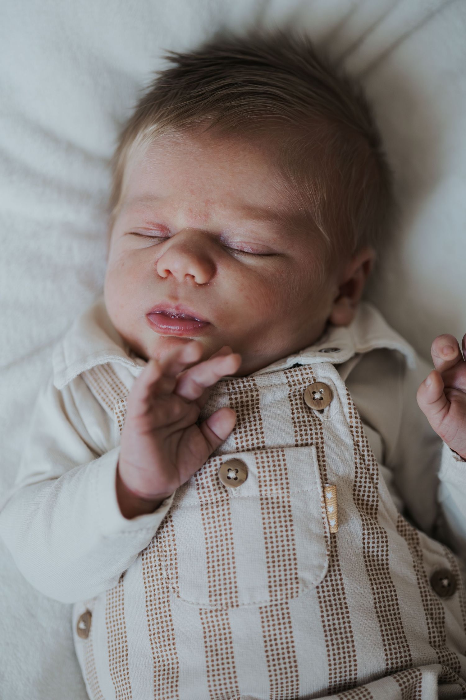 Pure newbornfoto van een pasgeboren baby in een warme, huiselijke omgeving.