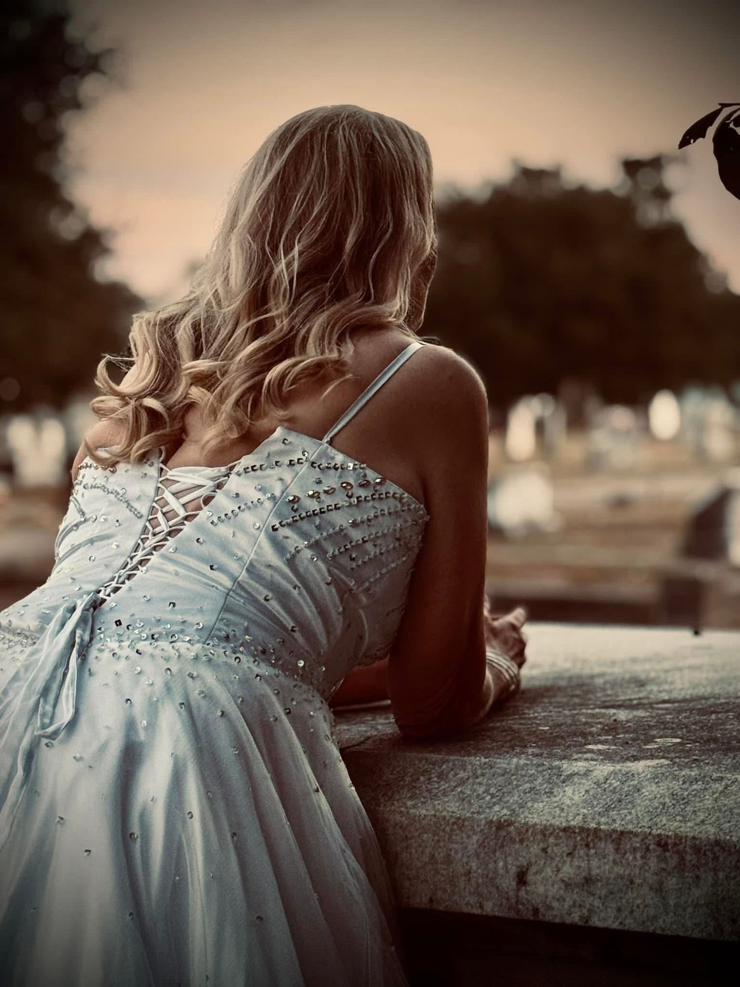 A series of sepia-toned photos showing a person in a light-colored lace dress leaning against a stone surface.