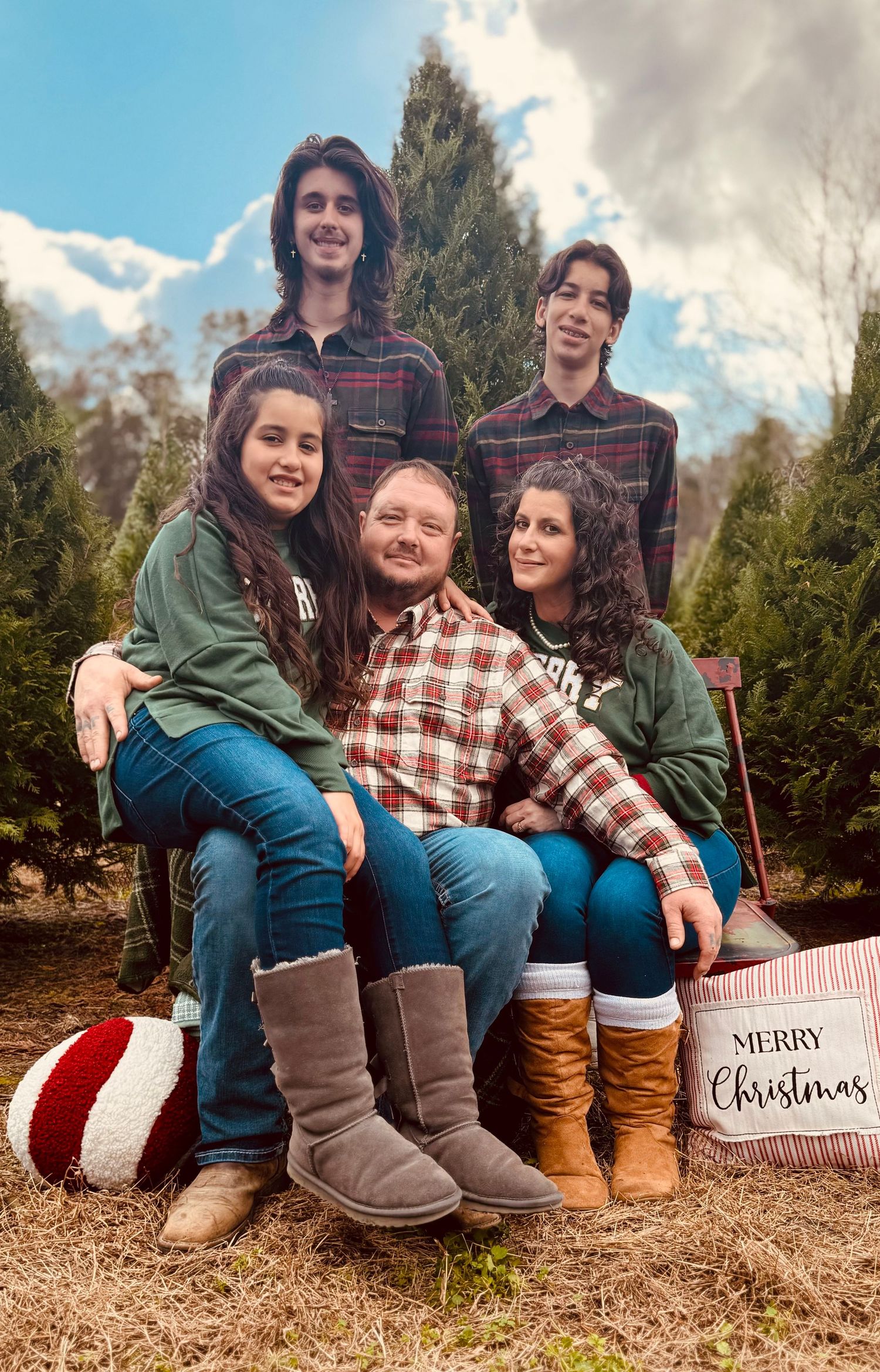 A family sits together outdoors for Christmas photos with plaid shirts and boots