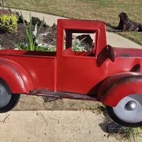 A bright red vintage pedal car with chrome trim and white wheels