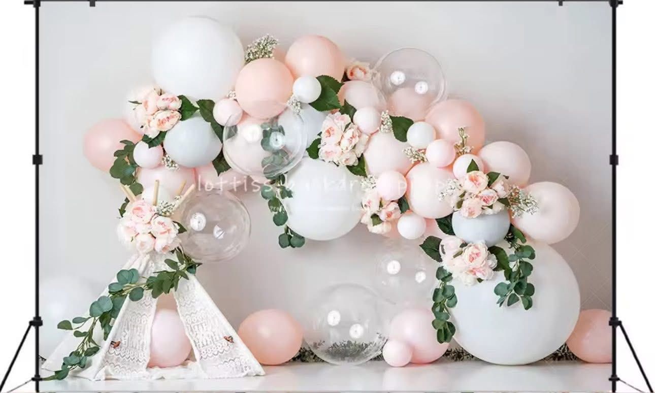 Pink and white balloon arch with eucalyptus greenery and floral accents creates an elegant party decoration.