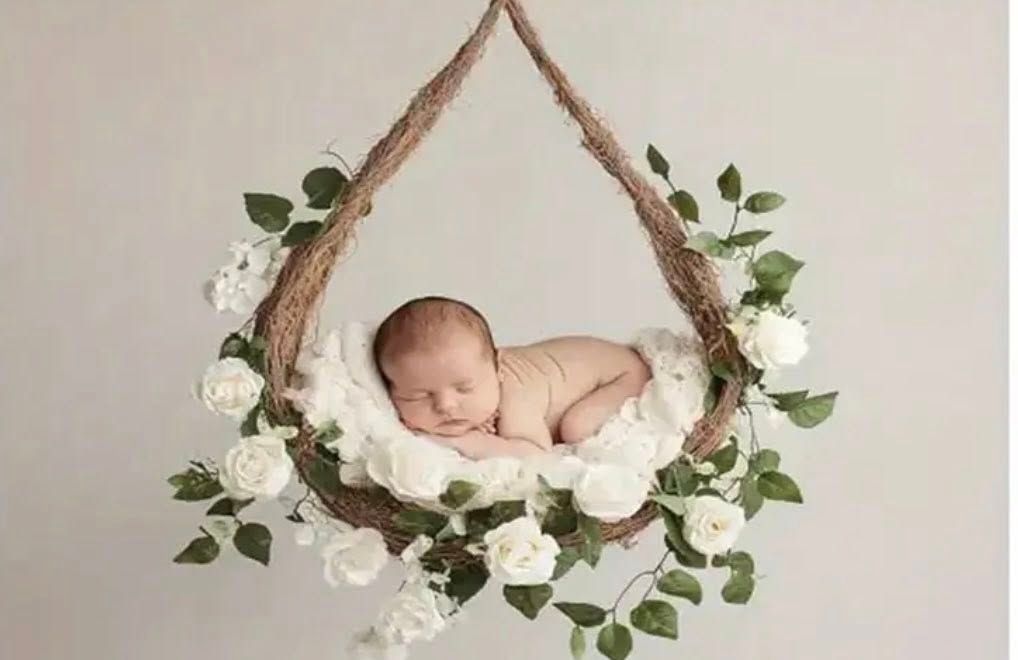 A rustic wooden swing adorned with white roses and green leaves.