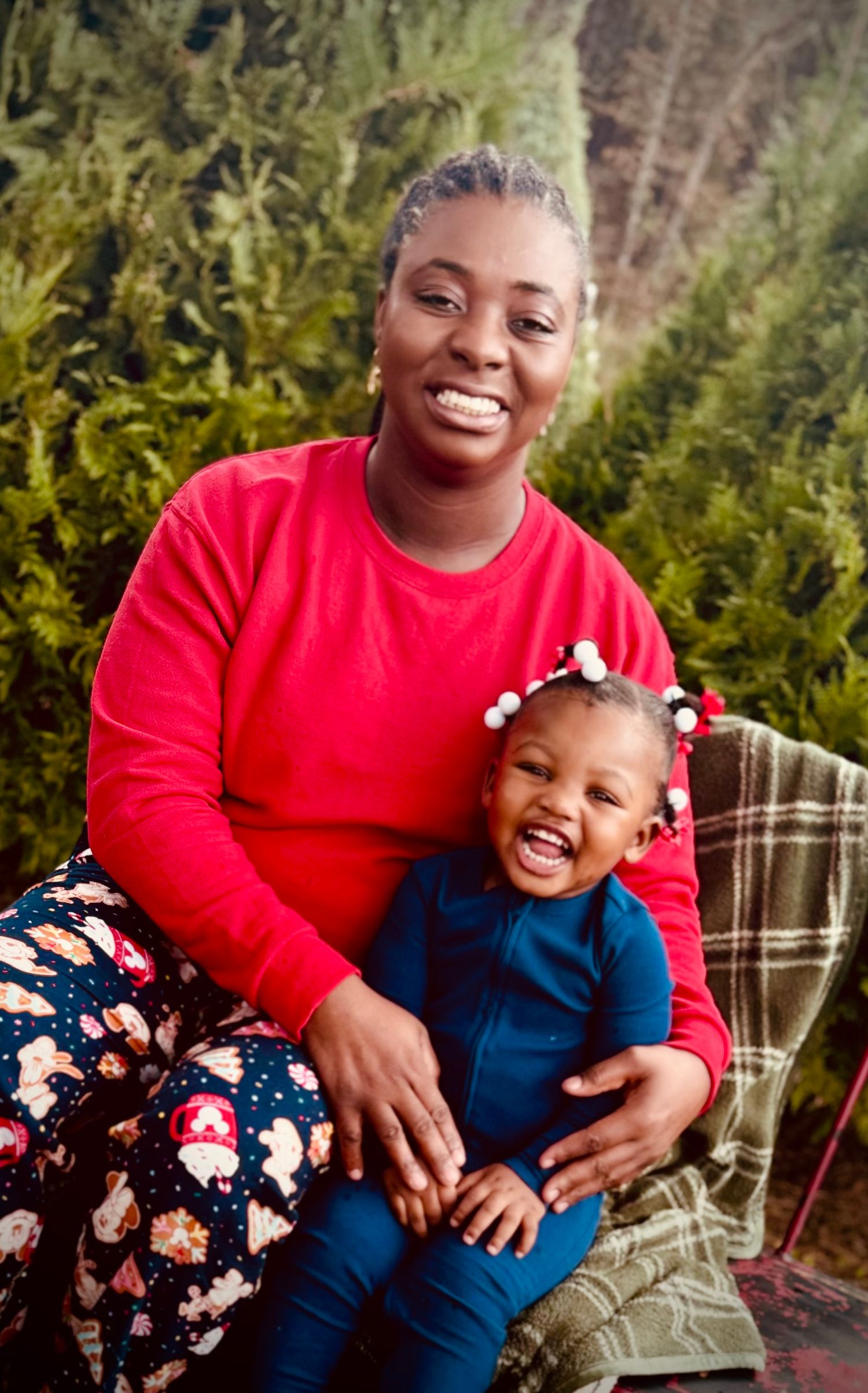 mother and daughter share joyful moments together while sitting outdoors among green foliage.