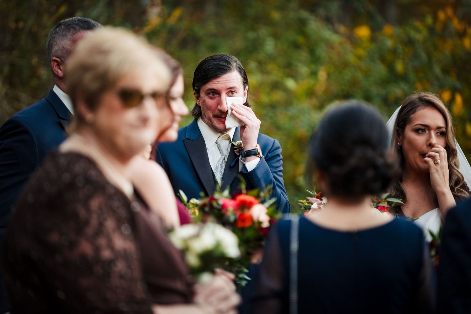 Wedding guests in formal attire observe the ceremony among fall foliage. Bittersweet Farm Rhode island wedding.