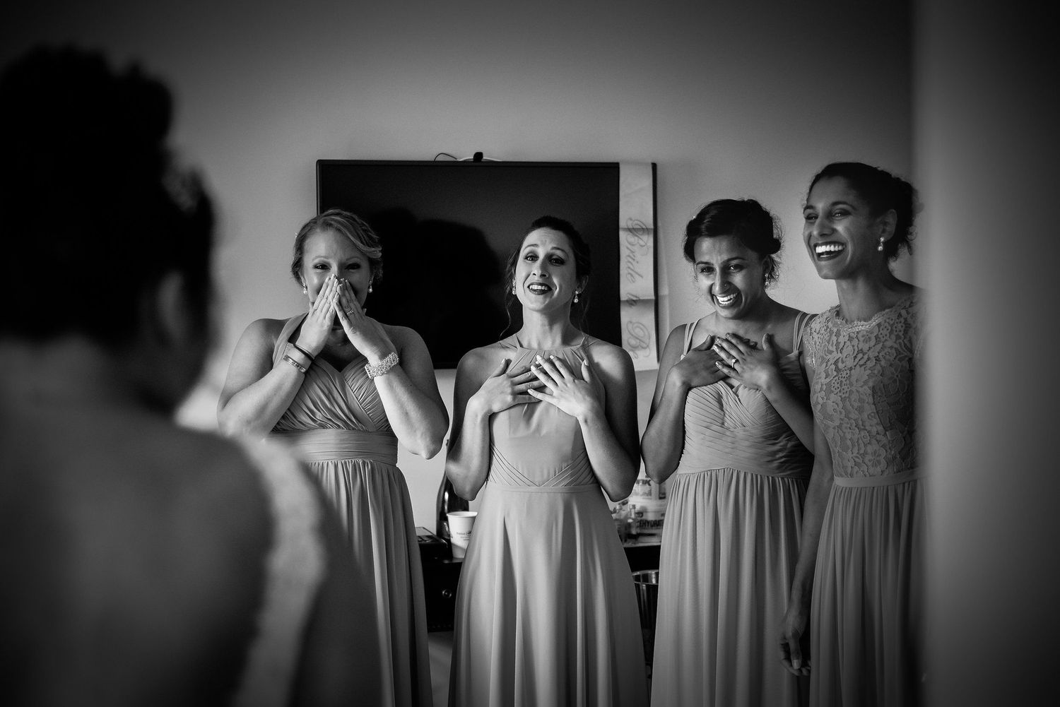 Black and white photo shows bridesmaids in matching dresses reacting emotionally. Taken by Rhode island wedding photographer