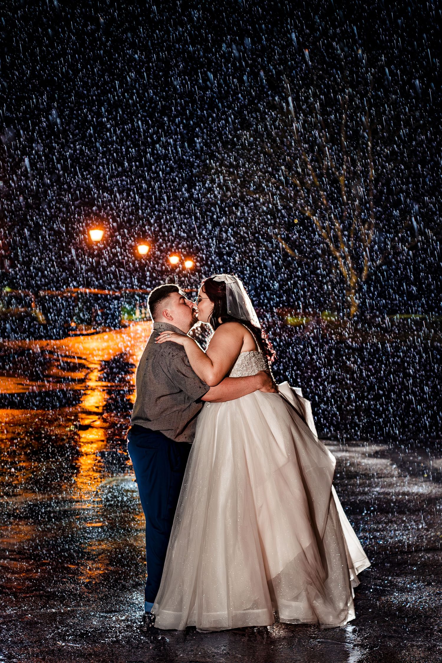 Romantic nighttime wedding photo with falling rain and glowing lights in the background. Taken by Rhode Island wedding Photographer