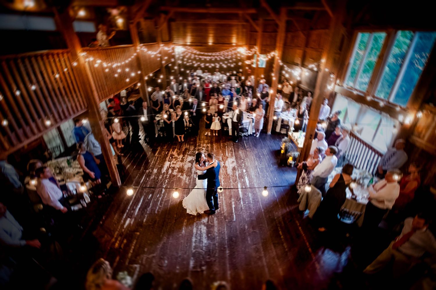 Wedding reception in rustic barn venue with string lights and dancing guests, photographed by a Rhode Island wedding photographer