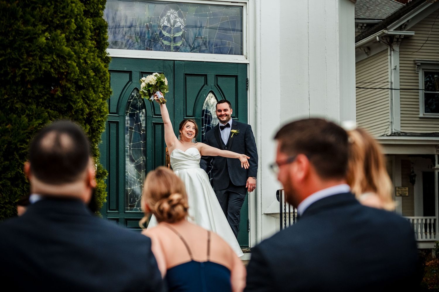 Wedding guests watch the ceremony in front of a white colonial-style building. Taken by Rhode Island wedding Photographer