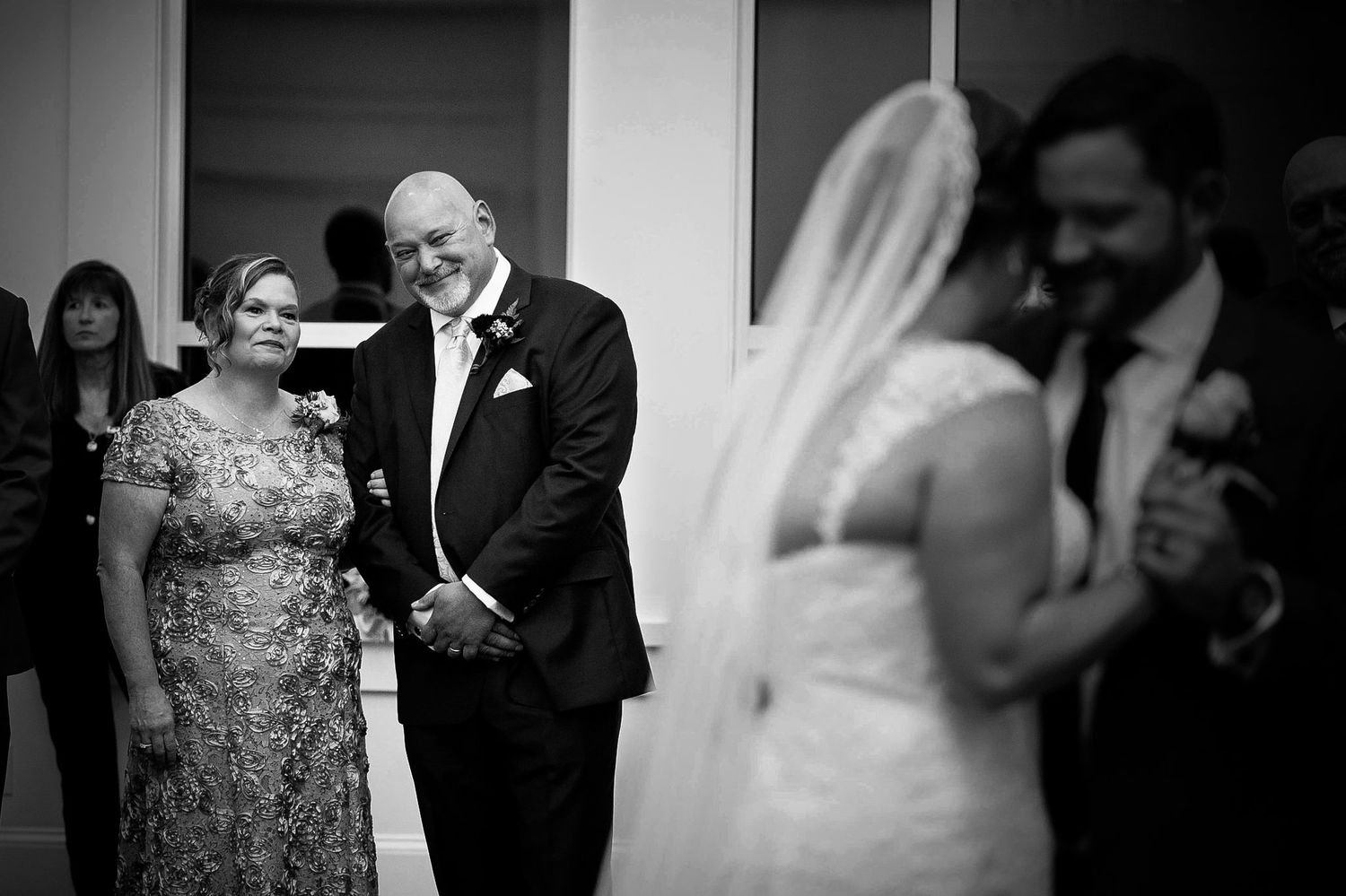 Wedding guests and party members gather in formal attire by doorway. Taken by Rhode island wedding photographer