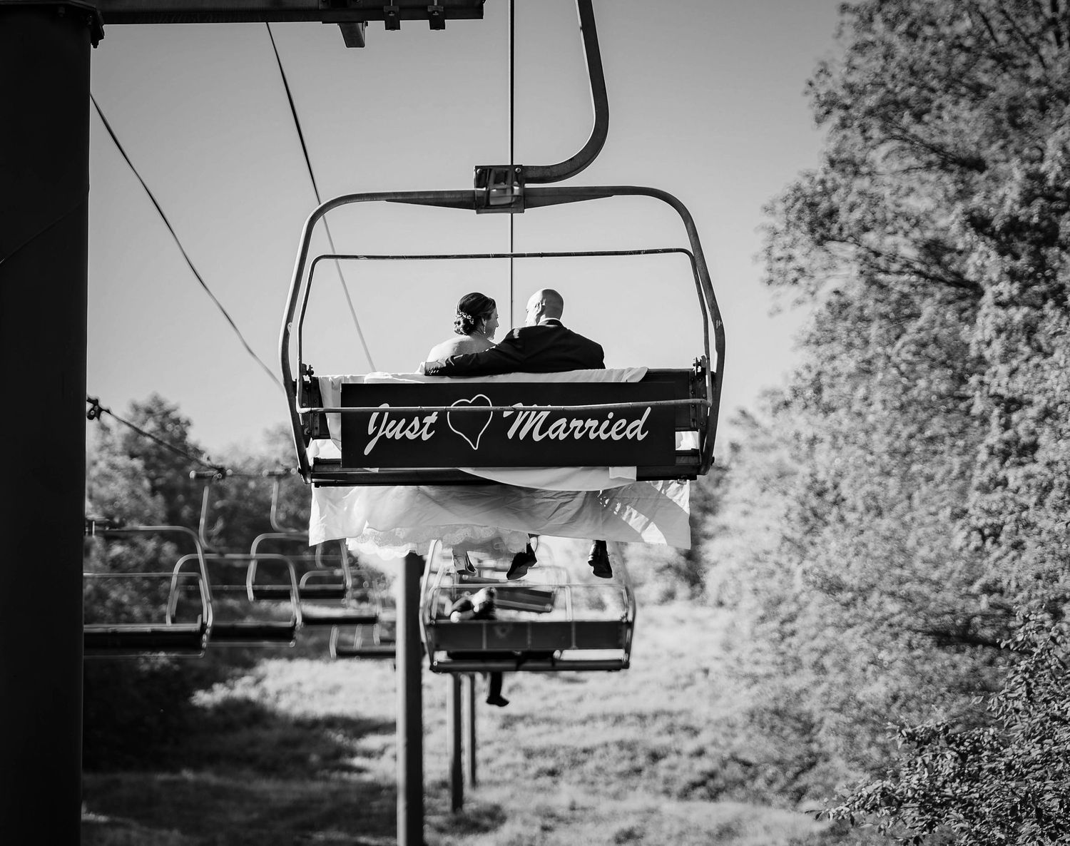 Ski lift chairs silhouetted against a bright sky with trees in the background.