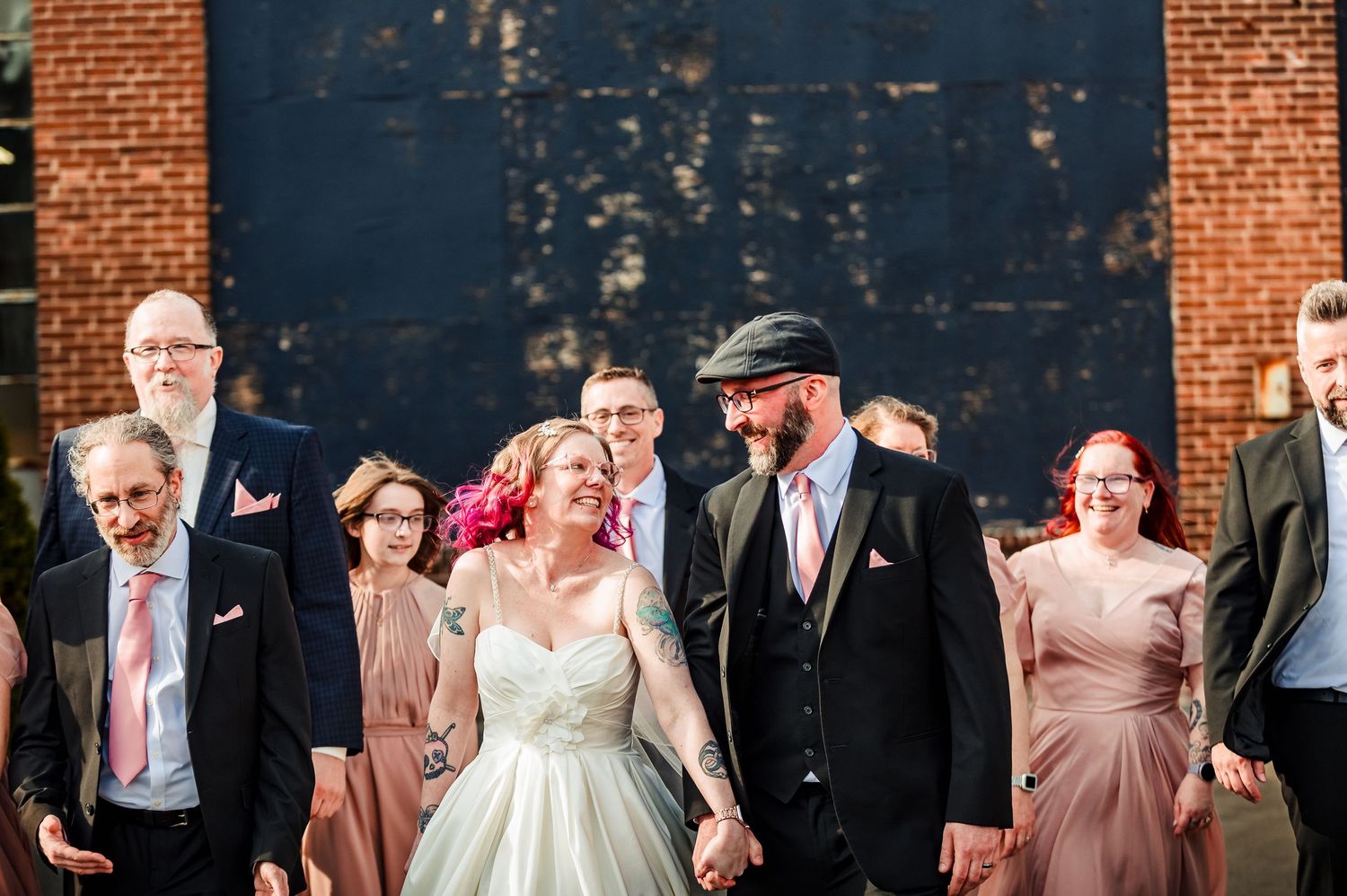 Wedding group poses against industrial brick wall backdrop at The Guild Brewery in Rhode island, Taken by Rhode Island wedding Photographer