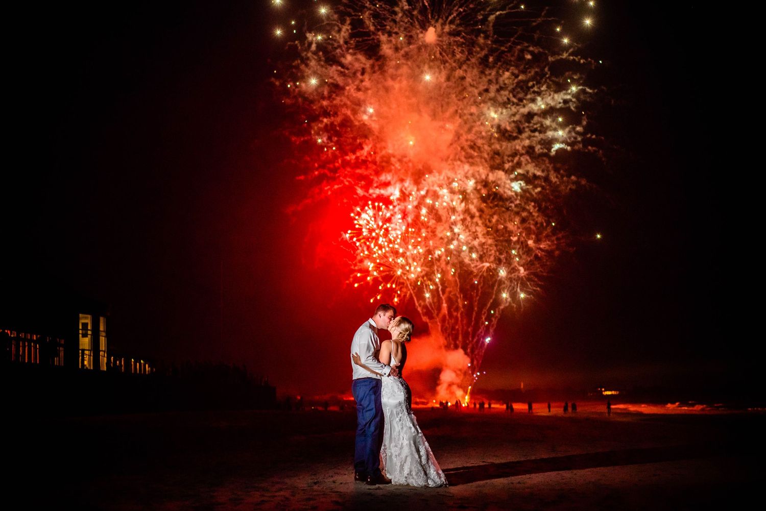 Fireworks illuminate the night sky behind a couple during their wedding celebration, photographed by a Rhode Island wedding photographer