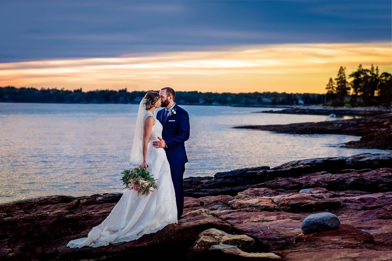 Sunset wedding captured on rocky coastline at Booth Bay Harbor ME with dramatic sky, photographed by a Rhode Island wedding photograper