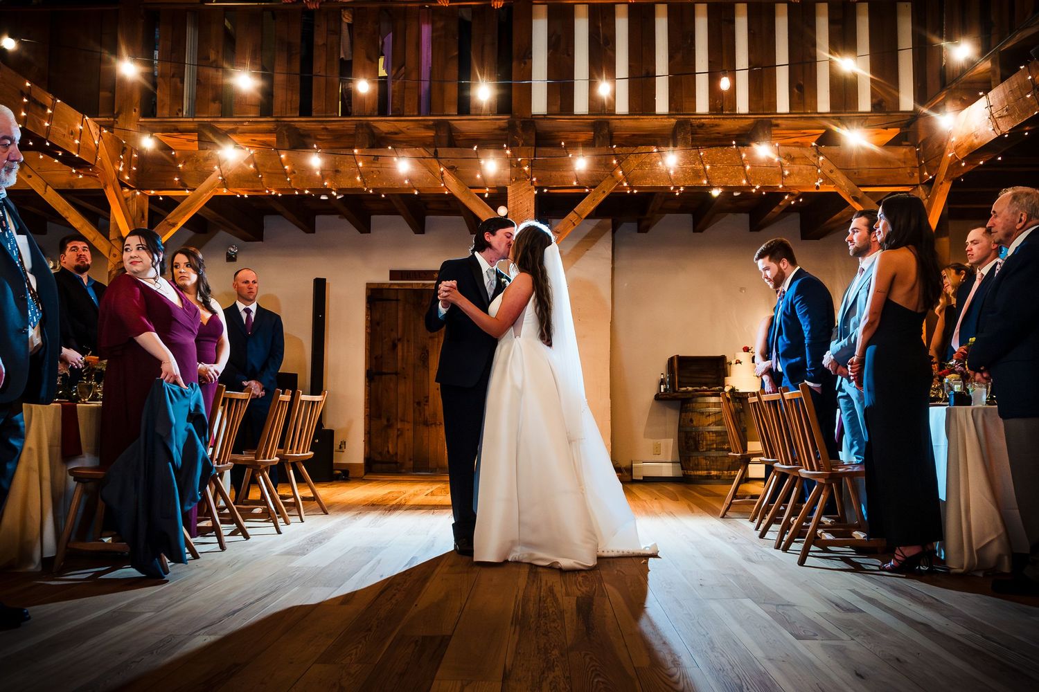 Wedding reception dance floor scene with warm lighting and wooden beams overhead. Bittersweet Farm Rhode island wedding.