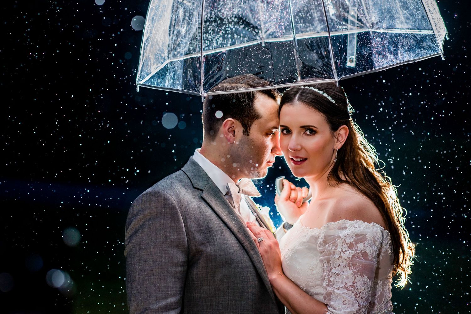 Romantic couple shares intimate moment under clear umbrella in the rain. Taken by Rhode Island Photographer