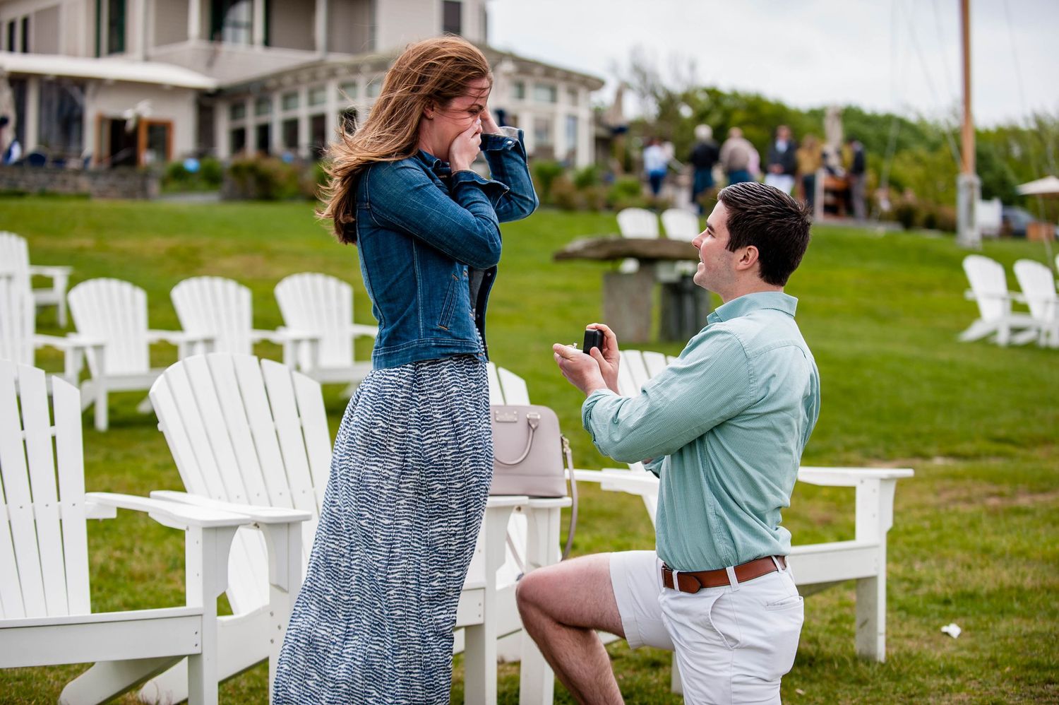 Marriage proposal scene with white Adirondack chairs on a waterfront lawn. Taken by Rhode Island Photographer