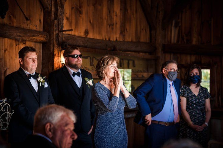 Wedding guests laugh and smile during an emotional moment at an indoor reception. Taken by Rhode island wedding photographer