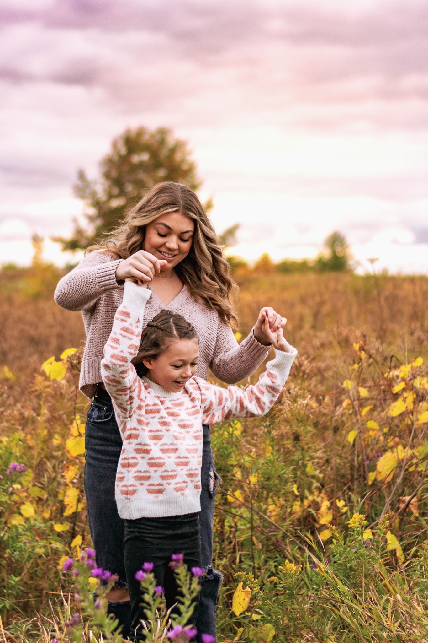 Playful moment between two people in a golden wildflower field at sunset.